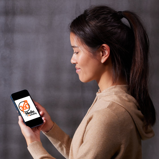 Woman looking at phone displaying 360 Media + Marketing